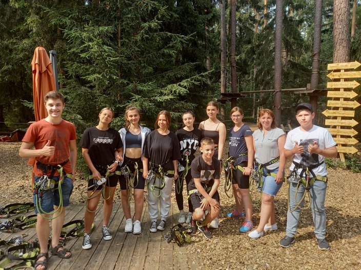 Die Gruppe steht mit Klettergurten angezogen im Wald.