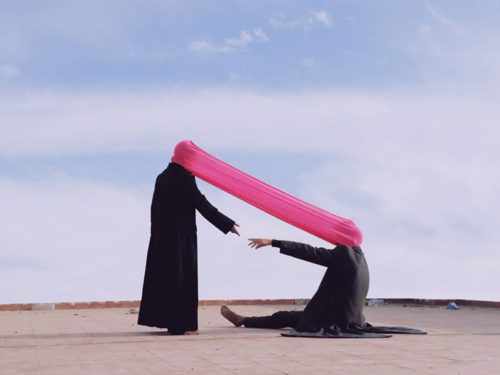 Das Foto In Touch des marokkanischen Fotografen Ismail Zaidy zeigt zwei Menschen, einen sitzend einen stehend, deren Köpfe mit einem pinken Tuch verbunden sind.