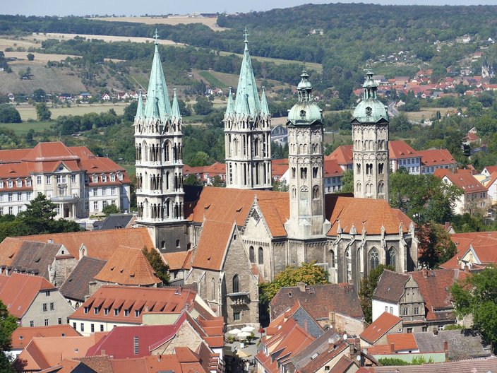 Blick auf den Naumburger Dom, im Vordergrund Häuserdächer, im Hintergrund Landschaft hinter der Stadt