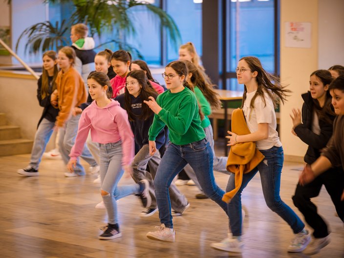 Schülerinnen und Schüler laufen durch einen Schulflur