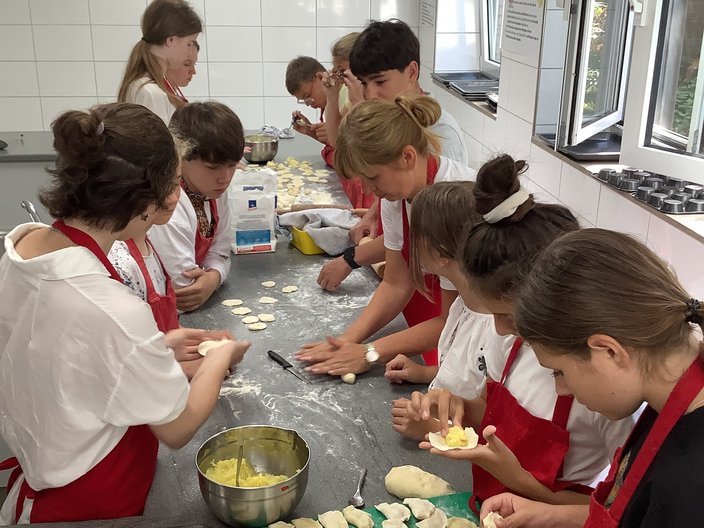 Schüler und Schülerinnen sind in der Schulküche und stellen gemeinsam Vereniki, ein ukrainisches Gericht, her.