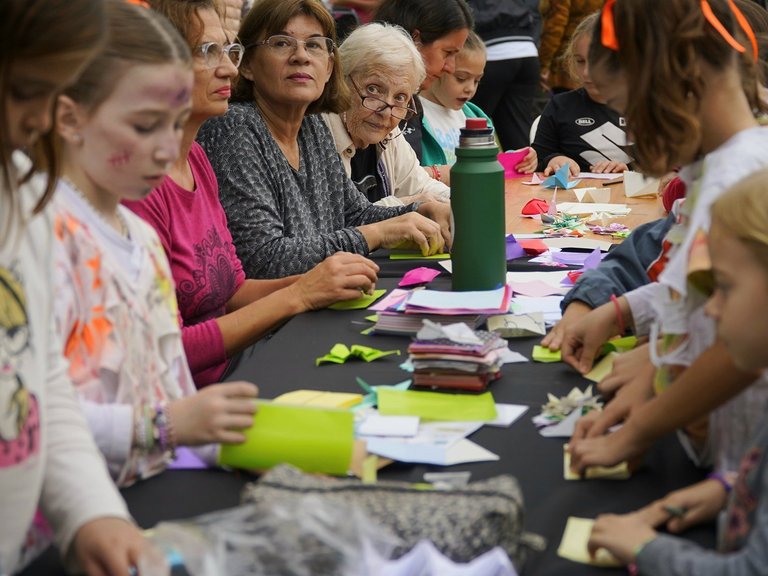 Kinder und Frauen basteln an einem langen Tisch.