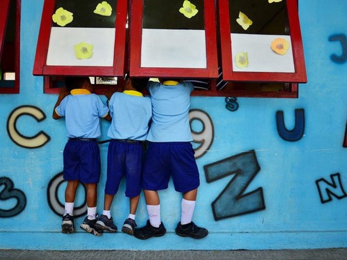 Drei Schulkinder vor einer bemalten Wand.