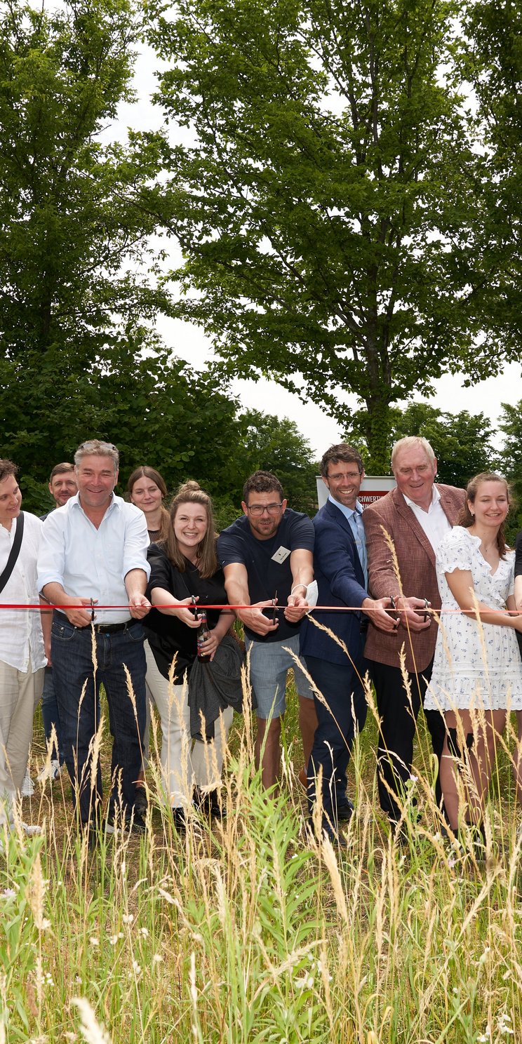 Schüler*innen stehen um die neue Klimastation herum und schneiden das Eröffnungsband.