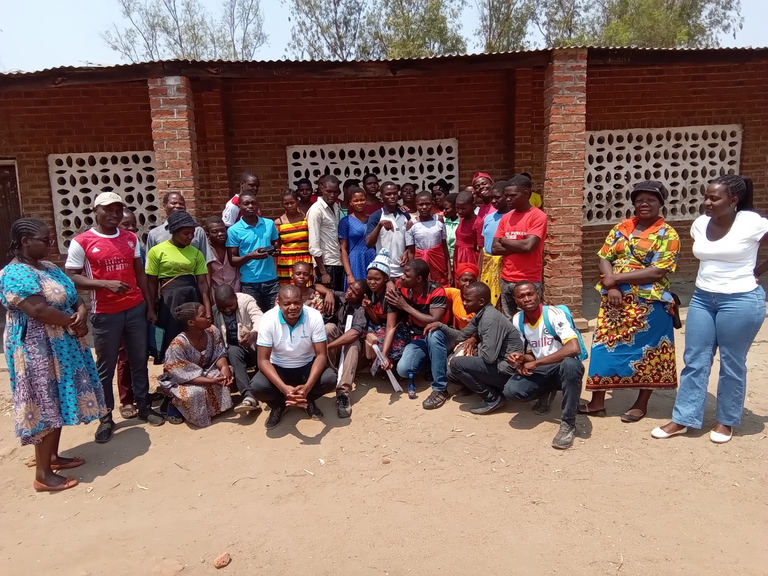 Eine Gruppe Teilnehmendes des MAB-Projektes in den Bioshärenreservaten Lake Chilwa Wetland und Mount Mulanje steht vor einem Haus. Die circa 20 Personen schauen lächelnd in die Kamera. 