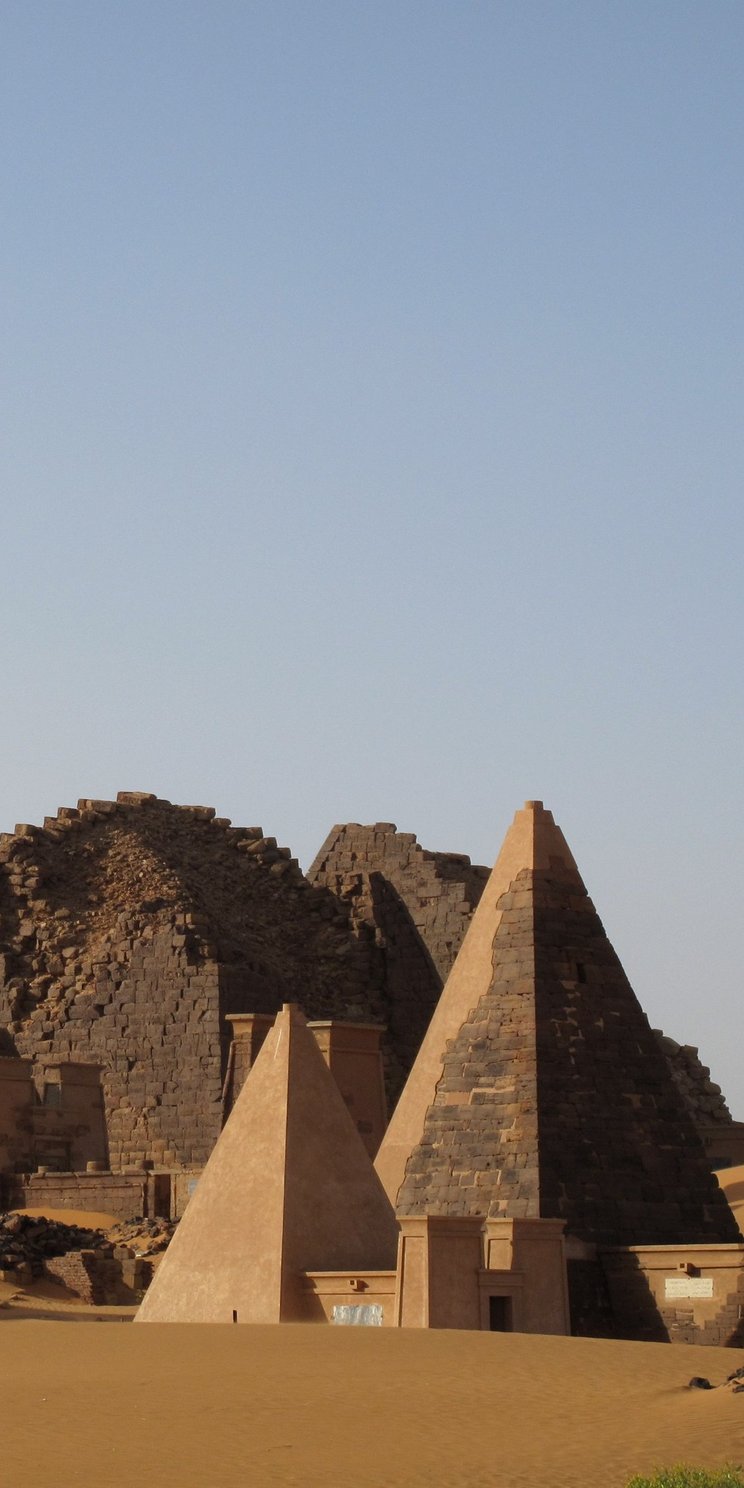 Blick auf die Welterbestätte Meroe. Man sieht pyramidenartige Gebäude, im Hinter