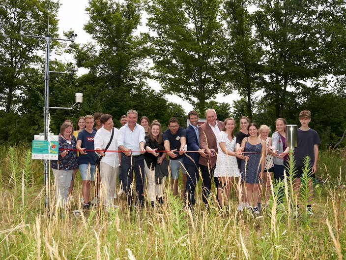 Schüler*innen stehen um die neue Klimastation herum und schneiden das Eröffnungsband.