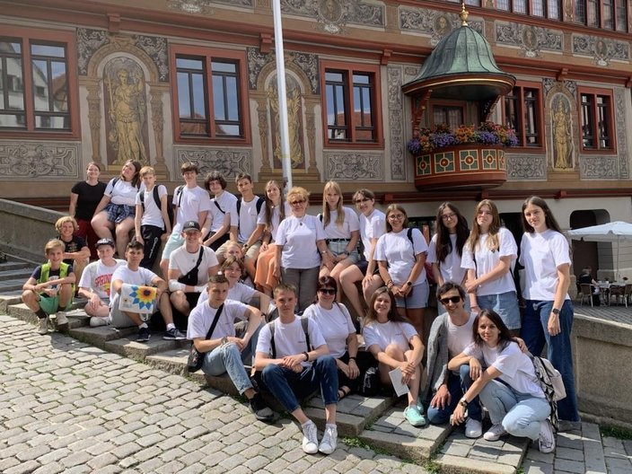 Die Gruppe steht und sitz für ein Foto auf der Brücke vor dem Rathaus in Tübingen.