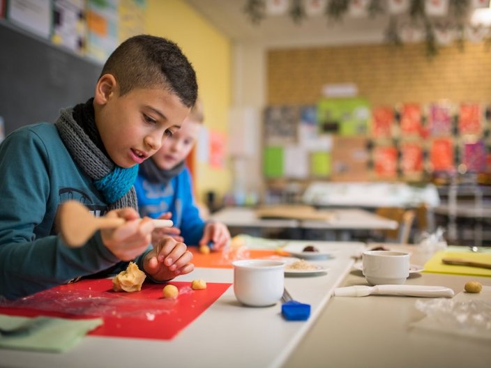 Grundschulkind in einem Klassenzimmer beim Backen.