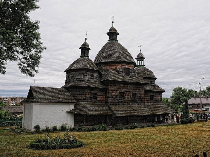 Blick auf eine dunkle Holzkirche mit drei Kuppeldächern